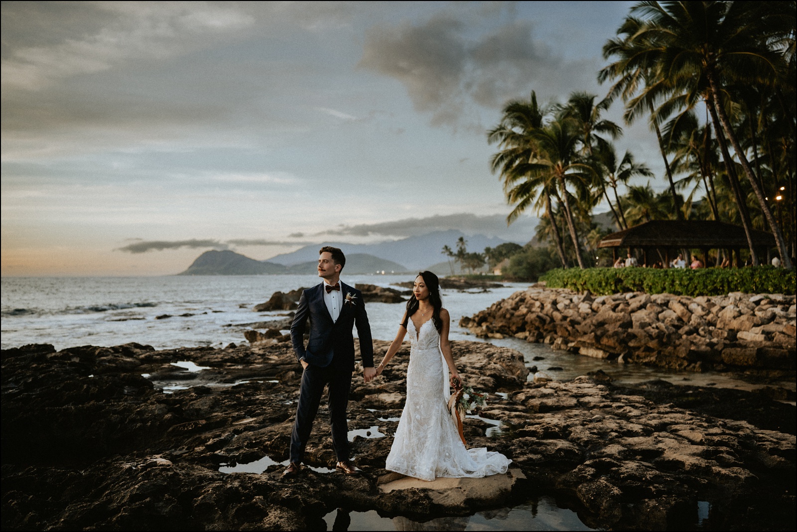 Bride and groom on the rocky shore fronting Lanikuhonua